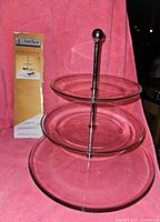 Full view of the 3-tier clear glass appetizer tray showing three stacked plates of different sizes on a metal rod with handle.