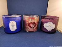 Front view of three candles showing their labels: Midnight Blue Citrus, Spice, Lavender Vanilla.