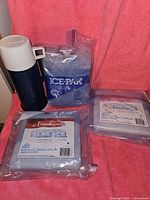 Photo of three square freezer ice packs and one blue and white thermos on a pink background.