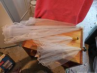 Three mesh food umbrellas folded and laid on a wooden surface, showing pointed handles with green grips and beige mesh material.