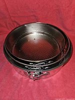 Three metal springform pans stacked, showing clasps and textured removable bottoms