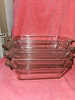 Stacked view of four clear glass loaf pans, three of the same size and one smaller