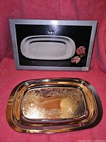 Silver plated rectangular serving tray with engraved ornate floral pattern, shown alongside its original box with tray image and decorative roses on front.