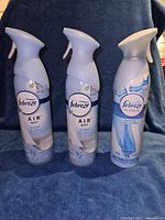 Front view of three Febreze spray cans showing labels and design for identification.