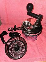 Manual multi-purpose chopping and mixing bowl set with attachments arranged on pink background.