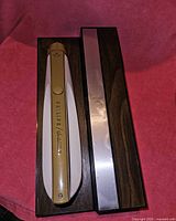 Closed view of Philips Switchblade electric cutting utensil in closed storage case with wood finish and metallic lid.
