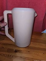 Side view of cream-colored Rubbermaid jug showing handle and smooth surface