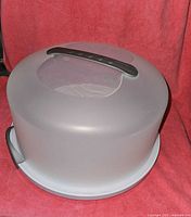 Top angled view of a translucent gray dome with black handle on top and white base plate below.