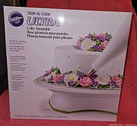 Front box label showing the product name, image of the turntable with decorated cake, and key features in multiple languages.