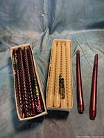 Two boxes of spiral taper candles, burgundy and ivory, plus two loose straight burgundy tapers