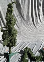 Artificial tree on stand with garland beside