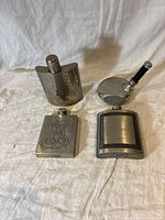 Photo showing all four pewter hip flasks from top side angle on white cloth background.