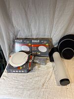 Photo of three HALO 6-inch LED downlights in packaging with one removed showing face and attached wiring and drivers.
