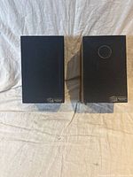 Pair of bookshelf speakers front view with black fabric grills covering drivers and AudioSphere Research logo on lower right corner