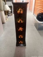 Front view of tall narrow wooden cabinet with five hand-painted floral drawers, dark finish, and slightly curved base.