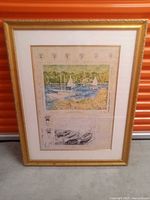 Framed artwork showing three sailboats on water, with trees in background and text below image.