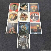 Top-down view of ten Sega Genesis Sega CD video game discs arranged in a grid on a grey carpet, displaying cover art directly on the discs.