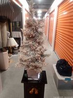 Full view of artificial flocked Christmas tree showing snow-effect on branches and potted base