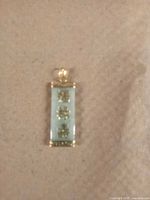 Front view of rectangular jade pendant with Chinese characters in gold and gold frame.