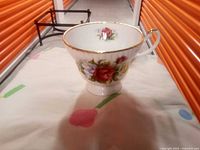 Teacup side view showing floral pattern and gold rim and handle trim.