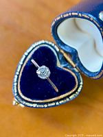 Close-up of ring in heart-shaped velvet box showing diamond and band