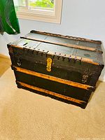 Front top side of trunk showing wooden slats, metal tacks, metal lock clasp and latches