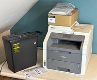 View showing both Brother printer and Amazon Basics shredder side by side on table with documents and box on top of printer.