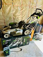Assembled EGO 21-inch cordless lawn mower with battery attached, charger and original box visible in background.