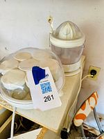 Photo showing the Euro Cuisine yogurt maker with multiple yogurt jars inside, covered by a clear dome lid, and the Juiceman Citrus Juicer next to it on a counter.