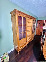 Full view of large antique rustic wooden cupboard with glass doors and drawers.