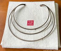 Front view of the tri-strand crescent choker necklace displayed on a white fabric surface.