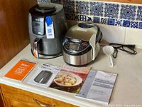 Ninja 4 quart air fryer and Tiger 5.5-cup rice cooker with manuals and rice paddle on countertop