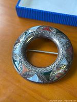 Front view of circular silver brooch with multicolored agate inlays