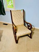 Front angle view of rocking chair showing upholstery pattern and wood frame details.