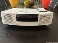 Front view of the Bose Wave Radio/CD unit showing the curved speaker grille and remote control on top.