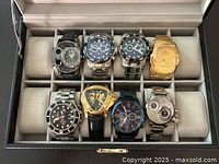 Top down view of eight watches in black leather storage case with individual slots