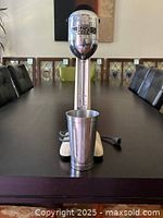 Full view of cream-colored Myers Bullet Mixer with aluminum cup placed on table.