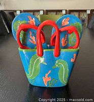 Front view of the ceramic beach bag showing red handles and seahorse and coral designs