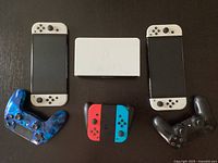 Two Nintendo Switch consoles with white Joy-Con controllers flanking a white dock, below a blue swirl DualShock 4, a Joy-Con grip with neon Joy-Con and a black DualShock 4