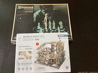 Boxes of Renaissance Chessmen chess pieces set and Marble Night City mechanical model kit shown together.