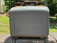 Closed Ryobi branded hard plastic carrying case for the circular saw, with handle and latches visible.
