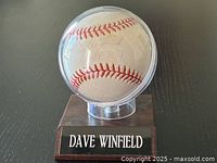 Clear display case containing the signed baseball on wooden base with "DAVE WINFIELD" plaque