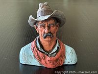 Front view of painted cowboy bust sculpture showing detailed face, hat, and clothing