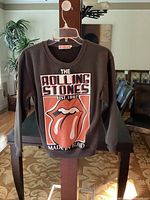 Front view of dark-colored sweatshirt with The Rolling Stones logo and text.