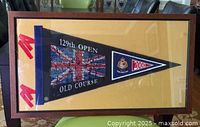 Full view of the 129th Open Old Course golf pennant framed with gold background and visible player names and 2000 flag