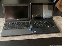 Front view of Dell and Lenovo laptops open on table showing keyboards and screens