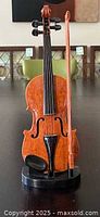 Full front view of violin on stand showing violin and bow, highlighting size and finish.