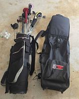 Two golf bags with assorted golf clubs, head covers, and golf balls on concrete floor.