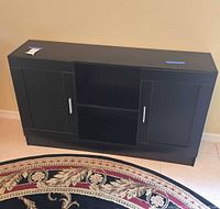 Front view of black storage cabinet with closed doors showing silver handles and black matte finish.