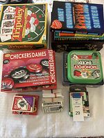 Overview of boxed board games and card decks showing Tripoley, Checkers, Monopoly Dice, and 3 decks of Bicycle cards.